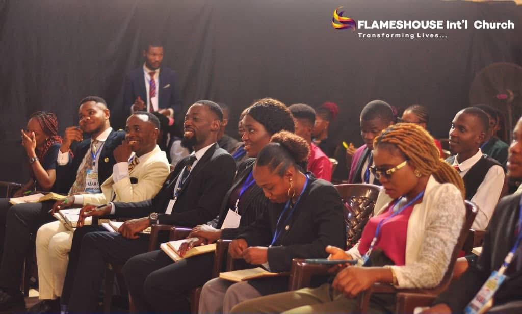 A large choir and worshipers with hands raised on a brightly lit stage